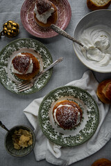 Homemade semlor buns with frangipane and whipped cream on vintage plates.