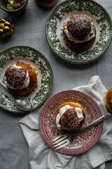 Homemade semlor buns with frangipane and whipped cream on vintage plates.