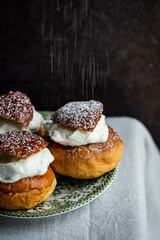 Homemade semlor buns with frangipane and whipped cream on vintage plate.