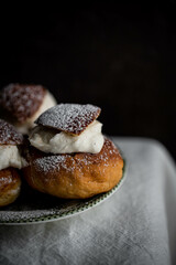 Homemade semlor buns with frangipane and whipped cream on vintage plate.