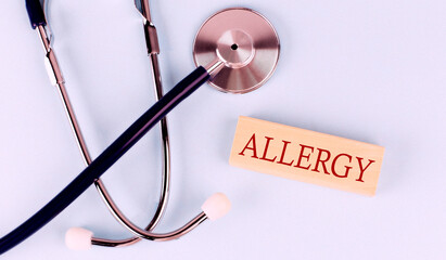 On a blue background, a stethoscope and wooden block with the word ALLERGY .Medical concept