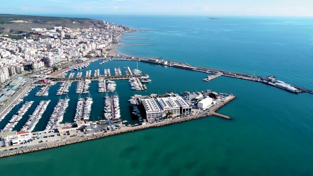 Aerial view of costal city Santa Pola. Situated in southeast of Spain Valencian Community is a famous travel destination. View of beautiful marina of Santa Pola. Baots docked. Drone pan left.
