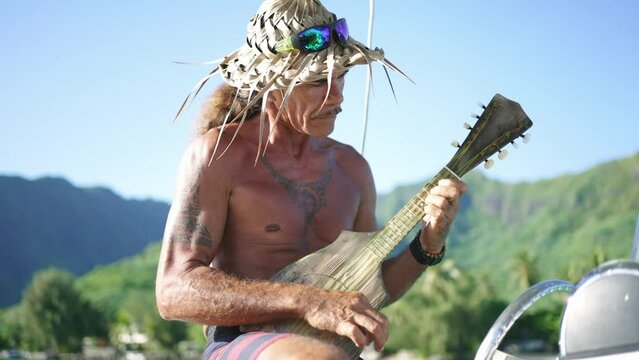 Traditional Polynesian man playing ukulele music on cultural tour in Bora Bora, Tahiti. French Polynesia. Exotic travel vacation getaway, romantic honeymoon destination.