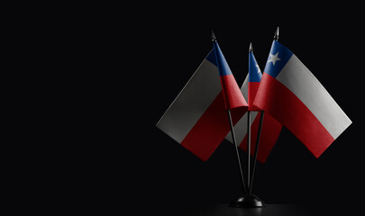 Small national flags of the Chile on a black background