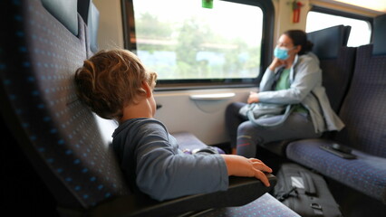 Child sitting on passenger seat inside train traveling on railroad transportation