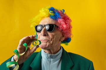 Front view of an old man dressed for carnival with sunglasses, green jacket, colored wig and green streamers