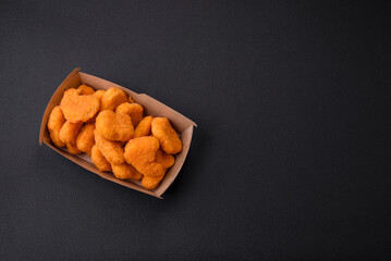 Delicious fresh crispy chicken nuggets on a dark concrete background