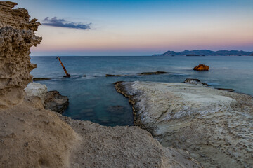 The white cliff of Sarakiniko at dusk with the wreck of a ship in mid-water, Milos island GR