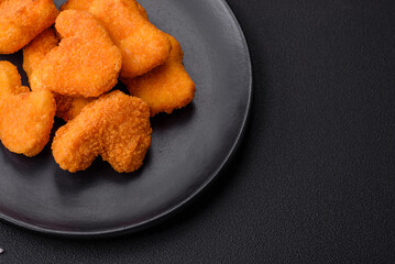 Delicious fresh crispy chicken nuggets on a dark concrete background