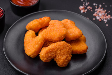 Delicious fresh crispy chicken nuggets on a dark concrete background