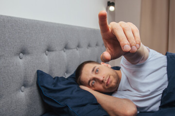 A sleepy young man holds out his hand to turn off the alarm. selective focus.