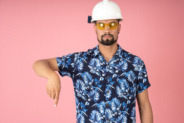 Worker with hard hat and protective glasses pointing downward