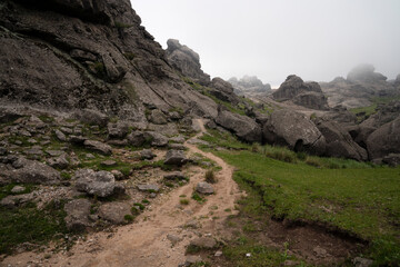 View of the hiking path across the rocky hill in a foggy early morning. 