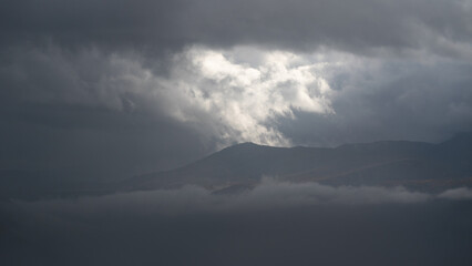 Dramatic landscape with mountain peak between fog and clouds, autumn season in mountains
