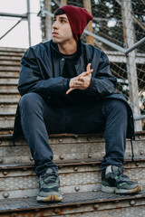 A young man sitting on outdoor staircase. One man alone sitting on stairs wearing winter clothing.