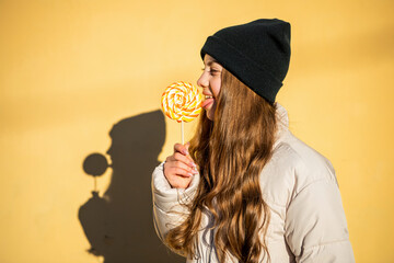 cheerful girl with yummy lollypop outdoor. girl with yummy lollypop wearing hat.