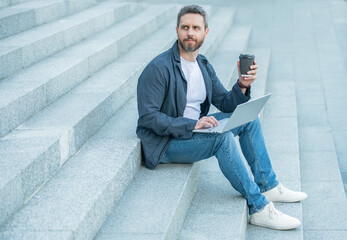 man blogging online with laptop outdoor at coffee break. man blogging online in the street.