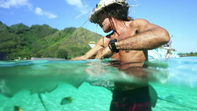 Underwater Tahiti. Traditional Polynesian man swims with sting ray. Bora Bora, French Polynesia. Exotic vacation activities, romantic getaway, honeymoon destination.
