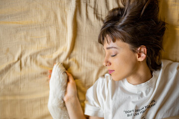 Woman holds dog's paw while sleeping together on bed, view from above. Relaxation and friendship...