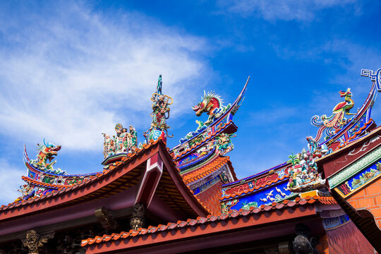 Ornate decoration on the roof of a Taiwanese temple building with the blue sky background