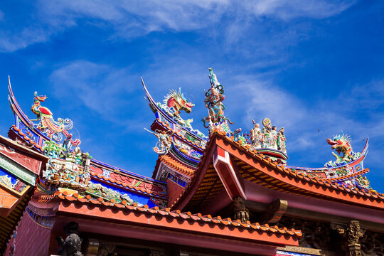 Ornate decoration on the roof of a Taiwanese temple building with the blue sky background