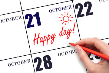 Hand writing the text HAPPY DAY and drawing the sun on the calendar date October 21