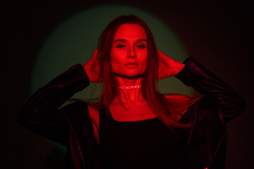 Cool fashionable trendy creative portrait of beautiful woman with red light on a dark green background