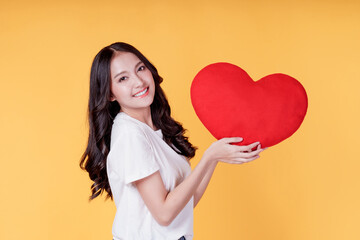 Love and valentines day. Happy Asian young woman long curly hair holding red heart smiling cute...