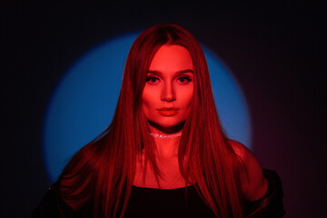 Female studio portrait of beautiful stylish woman with red creative light on dark background with blue circle in studio