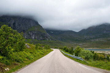 Scenic road along the fjords in Norway. Amazing landscape. Northern nature. Snow-capped mountains. Dramatic clouds. Travel, adventure