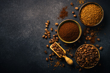 Roasted coffee beans, ground coffee and instant coffee in bowls at dark background.