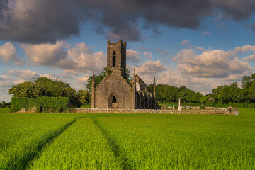 Tracks in cereal leading to old stone ruins and commentary of Ballinafagh Church with dramatic sky...