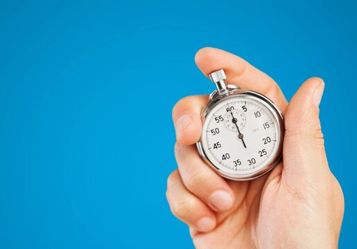 Classic clock in a human's hand on color background
