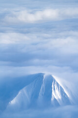 Fototapeta na wymiar Schneebedeckter Gipfel über Wolkenmeer