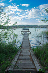 Fototapeta premium Pedestrian bridge to the pier with a bench in the lake