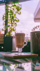 Fotografia a taza de cafe con un fondo de cafeteria a aire libre, con precencia de mucha luz y plantas en su fonfo