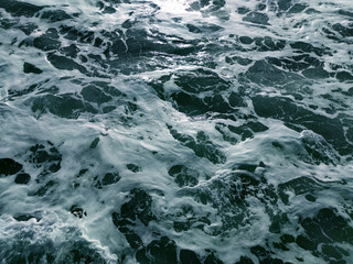 texture of turquoise sea water with white foam for water background