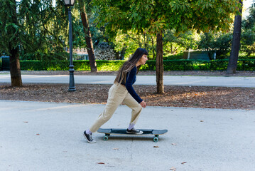 Young skateboarder woman practicing tricks with a longboard outdoors in a park.