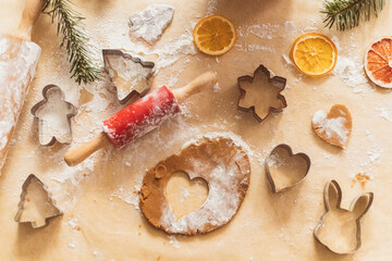 Top view of cookie dough with cut out shapes in the form of heart on brown parchment paper for the valentines day. 