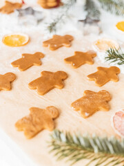 Homemade cookies in form of gingerbread men cut out and laid out on baking paper. Christmas time celebration
