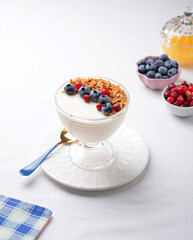 Creamy dessert with berries on white table