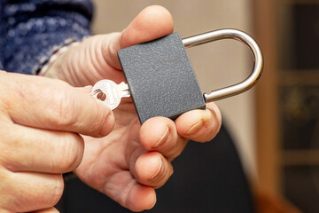 A man holds a padlock with keys in his hand