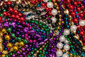 Many colorful mardi gras beads in a pile background