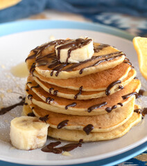 classic american breakfast. homemade banana pancakes on plate sprinkled powder and honey. A slide of hot pancakes with fresh bananas on a plate on the kitchen table . Pancake slide with honey topping