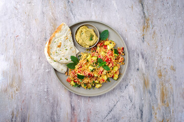 Traditional Moroccan vegetable couscous with pita bread and hummus served as top view on a Nordic Design plate with copy space