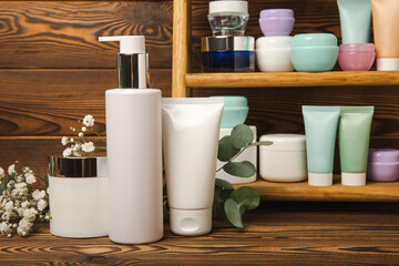 Fototapeta na wymiar Care cosmetics for face, body and hair on a wooden shelf. A set of cosmetic products shampoo, cream, serum and scrub on a shelf in the bathroom. Foreground. copy space. Beauty concept.