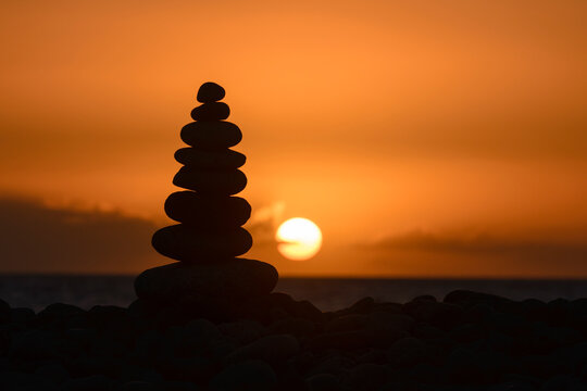 Silhouette of a stack of pebbles on beach at sunset, Playa de Arguineguin, Gran Canaria, Canary Islands, Spain