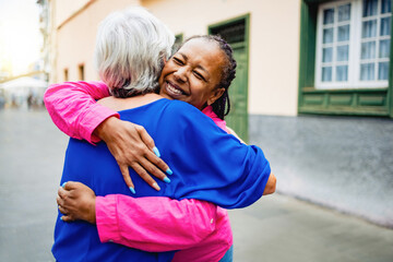 Multiracial senior women hugging each other - Elderly friendship and love concept - Soft focus on African female braids
