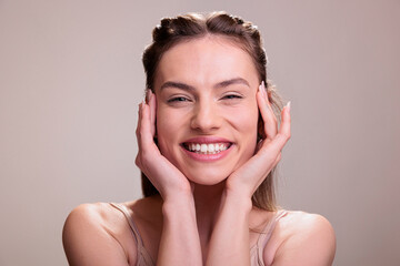 Happy smiling woman wearing natural make up holding hands on face portrait. Attractive model with...