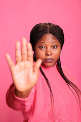 Irritated woman doing rejection gesture with hand in front of camera, concept of rejection and not accepting. Young adult showing stop gesture with palm, being in denial and expressing forbidden.